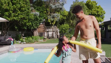 Happy-biracial-father-and-daughter-spending-time-at-pool-together