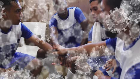 Animation-of-virus-cells-over-diverse-group-of-male-football-players-teaming-up-in-changing-room