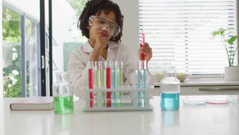 Happy-biracial-boy-making-chemistry-experiments,-holding-test-tube