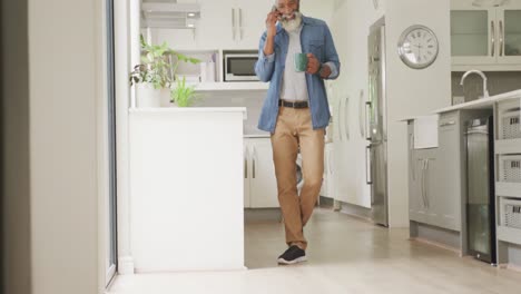 Video-Eines-Afrikanisch-glücklichen-älteren-Mannes,-Der-Kaffee-Trinkt-Und-Sein-Smartphone-Benutzt