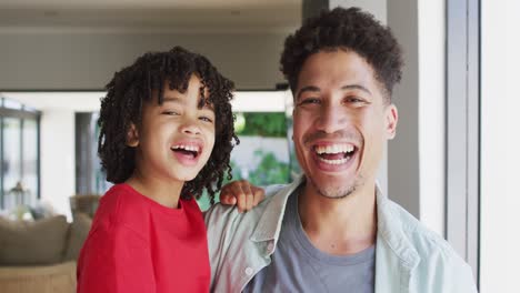 Portrait-of-happy-biracial-man-and-his-son-looking-at-camera-and-smiling