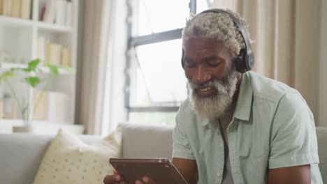 Video-of-african-american-senior-man-using-tablet-and-headphones
