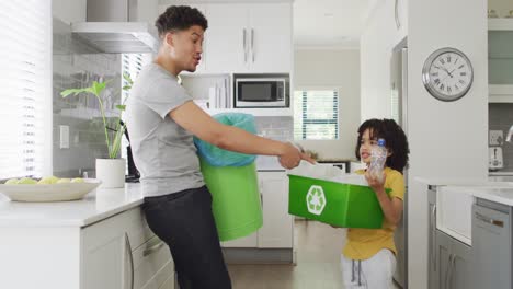 Happy-biracial-man-and-his-son-sorting-waste-in-kitchen