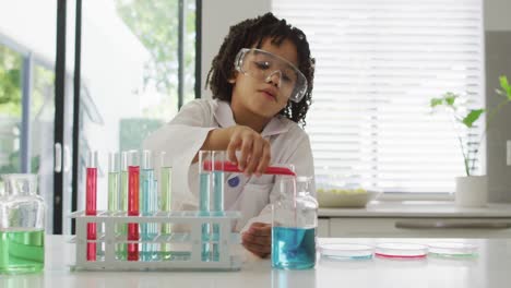 Happy-biracial-boy-making-chemistry-experiments,-holding-test-tube