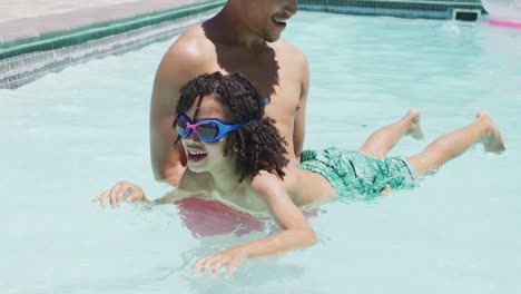 Happy-biracial-man-and-his-son-swimming-in-garden