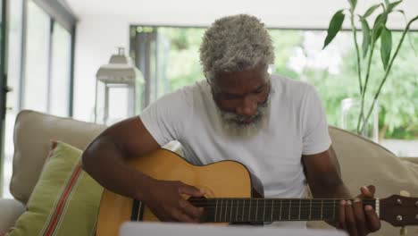 Video-Eines-Traurigen-Afroamerikanischen-älteren-Mannes,-Der-Gitarre-Spielt-Und-Einen-Laptop-Benutzt