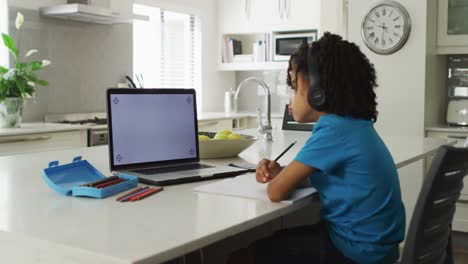 Feliz-Niño-Birracial-Sentado-En-La-Mesa-Usando-Una-Computadora-Portátil-Con-Espacio-Para-Copiar-Y-Teniendo-Clases-En-Línea