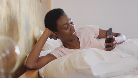 Afroamerikanische-Frau-Lächelt-Und-Benutzt-Allein-Ihr-Smartphone-In-Ihrem-Schlafzimmer