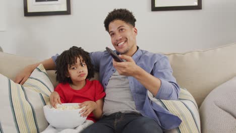 Happy-biracial-man-and-his-son-watching-tv-together