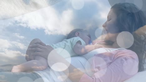 Animation-of-clouds-over-caucasian-mother-sleeping-with-her-baby