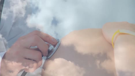 Animation-Von-Wolken-über-Einem-Kaukasischen-Arzt,-Der-Eine-Kaukasische-Schwangere-Frau-Untersucht