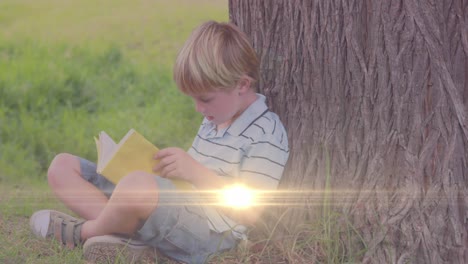 Animation-of-light-trails-over-caucasian-boy-reading-book