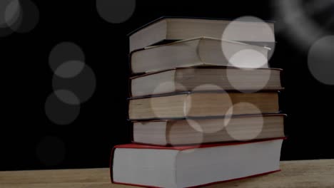 Animation-of-light-spots-over-books-on-black-background
