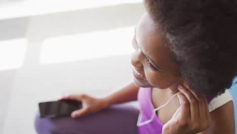 Happy-african-american-wearing-sportswear-and-earphones,-exercising