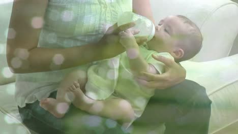 Animation-Von-Lichtflecken-über-Einer-Gemischtrassigen-Mutter,-Die-Ihr-Baby-Füttert