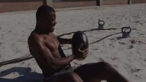 Bunte-Lichtpunkte-Vor-Einem-Fitten-Afroamerikanischen-Mann,-Der-Am-Strand-Mit-Einem-Medizinball-Trainiert