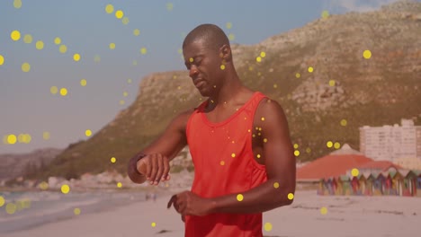 Animation-Von-Flecken-über-Einem-Afroamerikanischen-Mann,-Der-Am-Strand-Eine-Smartwatch-Benutzt