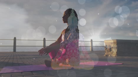 White-spots-of-light-falling-against-african-american-fit-woman-performing-yoga-on-the-promenade