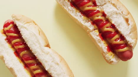 Video-of-hot-dogs-with-mustard-and-ketchup-on-a-yellow-surface