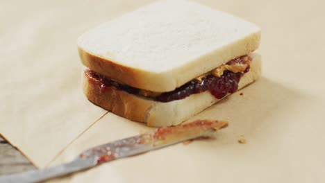 Close-up-of-peanut-butter-and-jelly-sandwich-and-butter-knife-on-wooden-tray