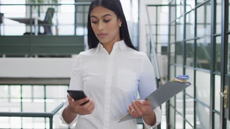 Happy-biracial-businesswoman-using-smartphone-at-office