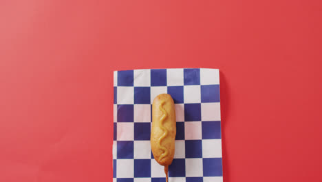 Video-of-corn-dog-with-mustard-on-a-red-surface