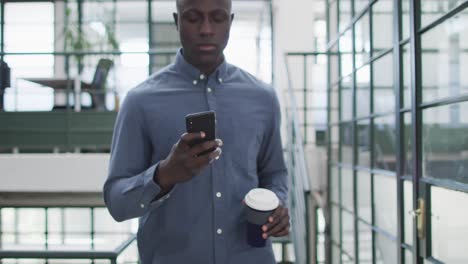 Happy-african-american-businessman-using-smartphone-at-office
