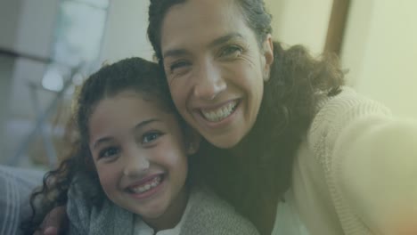 Animation-of-light-spots-over-biracial-mother-and-daughter-smiling-at-home