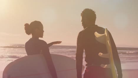 Animation-of-light-spots-over-african-american-couple-with-surfboards-at-beach
