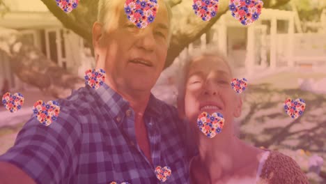 Animation-of-heart-icons-over-happy-senior-caucasian-couple-in-garden