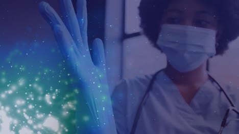Animation-Von-Lichtflecken-über-Einer-Afroamerikanischen-Ärztin,-Die-Medizinische-Handschuhe-Trägt