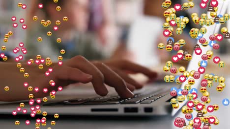 Animation-of-emoticons-floating-over-hands-of-caucasian-child-writing-on-laptop