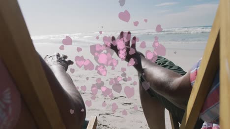 Animation-of-heart-icons-over-african-american-couple-lying-at-beach