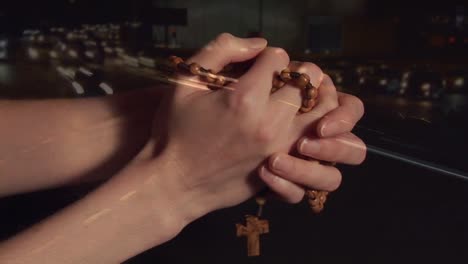 Animation-of-hands-of-caucasian-woman-holding-rosary-and-praying-over-road-traffic