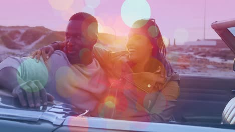 Animation-of-spots-over-happy-diverse-couple-embracing-in-car