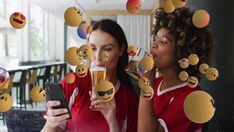 Animation-Von-Emoji-Symbolen-über-Glücklichen,-Vielfältigen-Freundinnen,-Die-Ihr-Smartphone-Mit-Bier-Benutzen