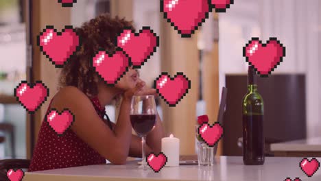 Animation-of-heart-icons-over-happy-biracial-woman-with-wine-having-laptop-video-call
