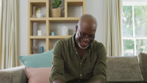 Porträt-Eines-Lächelnden-älteren-Afroamerikanischen-Mannes,-Der-Im-Wohnzimmer-Einen-Videoanruf-Tätigt