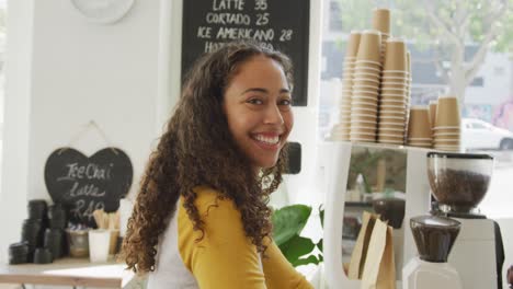 Portrait-of-happy-biracial-female-client-looking-at-camera-and-smiling-at-cafe