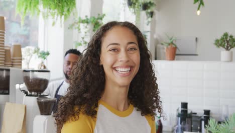 Portrait-of-happy-biracial-woman-looking-at-camera-and-smiling-at-cafe