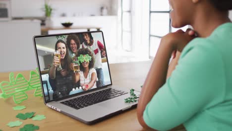 Smiling-diverse-group-of-friends-with-beer-wearing-clover-shape-glasses-on-video-call-on-laptop