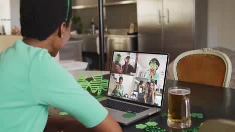 Smiling-diverse-group-of-friends-with-beer-wearing-clover-shape-items-on-video-call-on-laptop