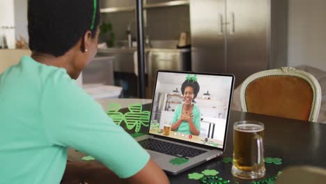 Lächelnde-Afroamerikanische-Frau-Mit-Bier-Und-Kleeblattband-Bei-Einem-Videoanruf-Auf-Dem-Laptop