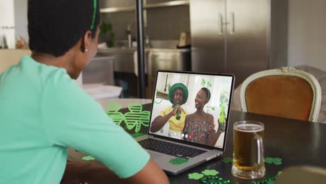 Pareja-Afroamericana-Sonriente-Con-Cerveza-Usando-Artículos-En-Forma-De-Trébol-En-Videollamada-En-Una-Computadora-Portátil