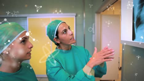Animation-Von-Molekülen-über-Zwei-Kaukasischen-Ärztinnen,-Die-über-Röntgenfotos-Sprechen