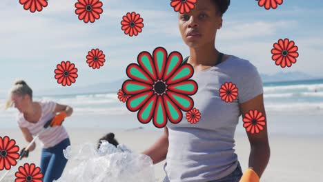 Animation-of-flowers-over-african-american-female-volunteer-picking-up-rubbish-on-beach