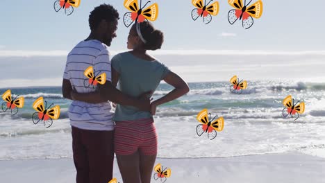 Animation-of-butterflies-over-back-view-of-african-american-couple-embracing-at-beach