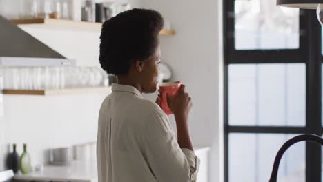 Glückliche-Afroamerikanische-Frau,-Die-Kaffee-In-Der-Küche-Trinkt