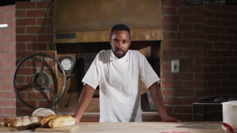 Animation-of-happy-african-american-male-baker-smiling-at-camera-in-bakery