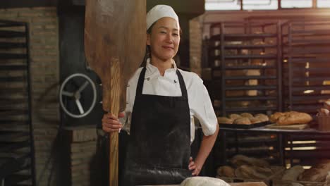 Animation-of-happy-asian-female-baker-holding-wooden-spatula